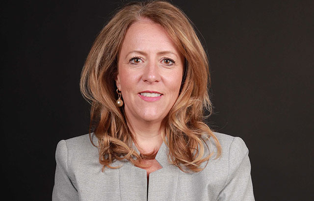 Professor Maxi Scherer smiling in a silver/grey suit.