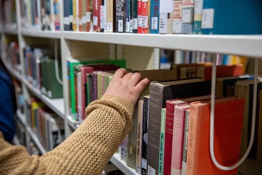 A student reaching for a book in the library