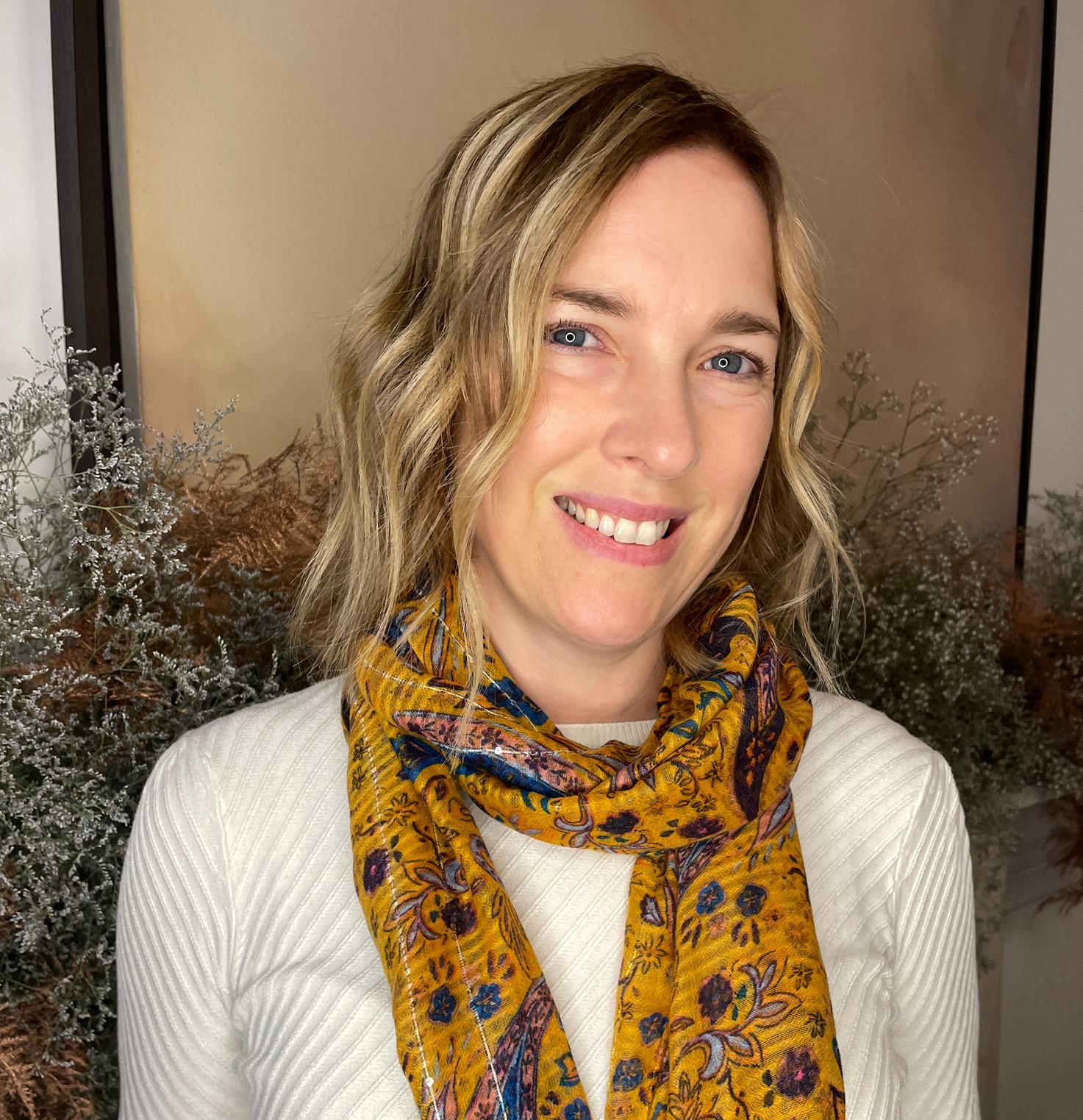 Dr Debbie Darling portrait photo. She is smiling and facing the camera. She's wearing a gold-colour patterned scarf and a cream coloured top.