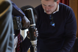 A trainee drilling into simulation bone while trainer observes