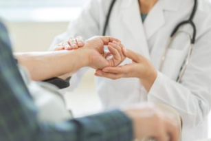 A doctor examining a patient's hand and arm