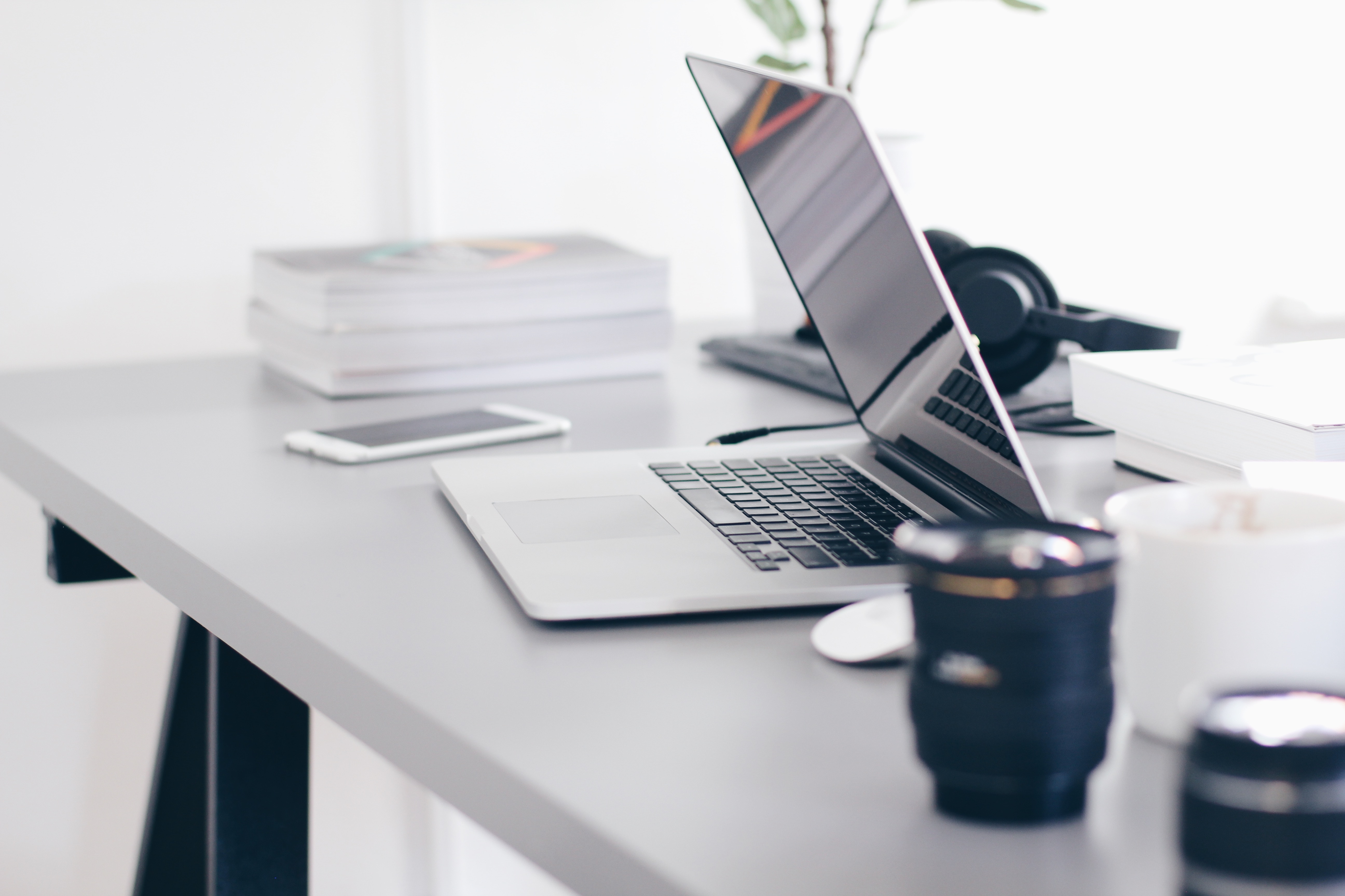 A half closed silver laptop is sitting on a grey desk