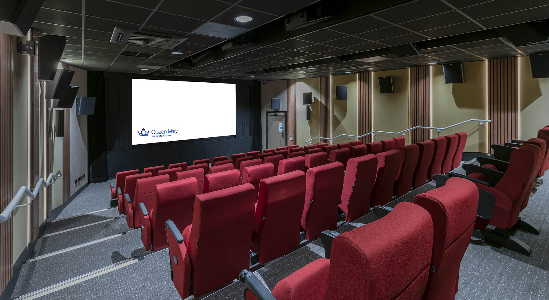 A cinema with raked seating with red seats and a pale yellow walls