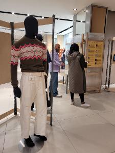 Mannequins dressed in garments made by women of he Dorcas Clubs. People are viewing the garments and notice boards in the gallery.