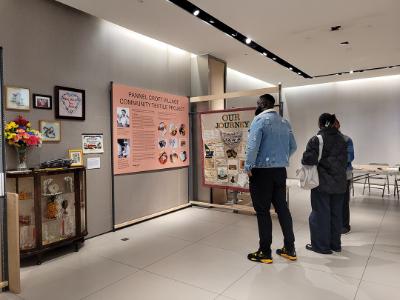 People standing in an art gallery looking at the Dorcas stories exhibition.