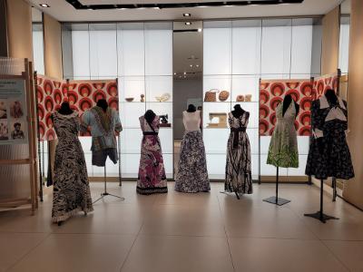 A series of mannequins with dresses with nature designs. Behind them are sculptures and sowing machines arranged on shelves