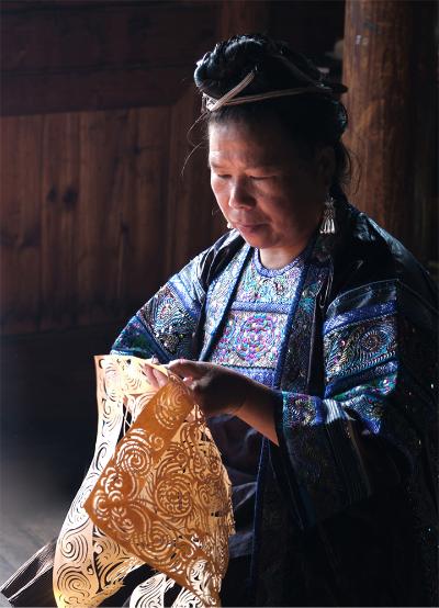 A woman from Guizhou practising Miao paper-cutting.
