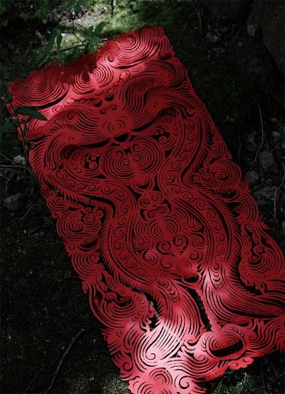 Miao paper-cutting example in red. The design is an hour glass of elaborate symmetrical patterns forming a dragon.