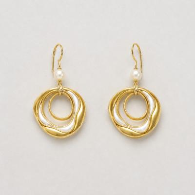 Gold earrings with freshwater pearl in a circular design.
