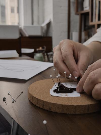 A person using pins to outline the design of a borach.