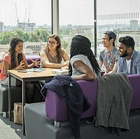 Group of students sitting around a table in the library discussing work 