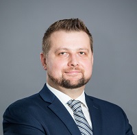 Smiling man with beard in navy suit and grey tie