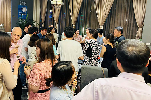 An alumni event with former students speaking to Ioannis at a reception.