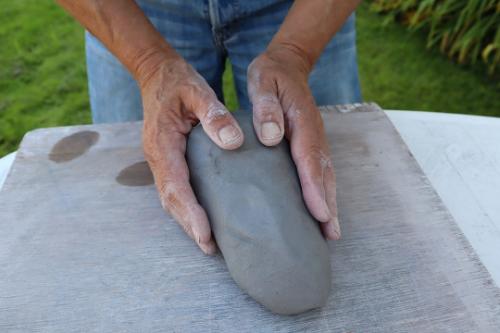 Someone molding some clay on a slate board.