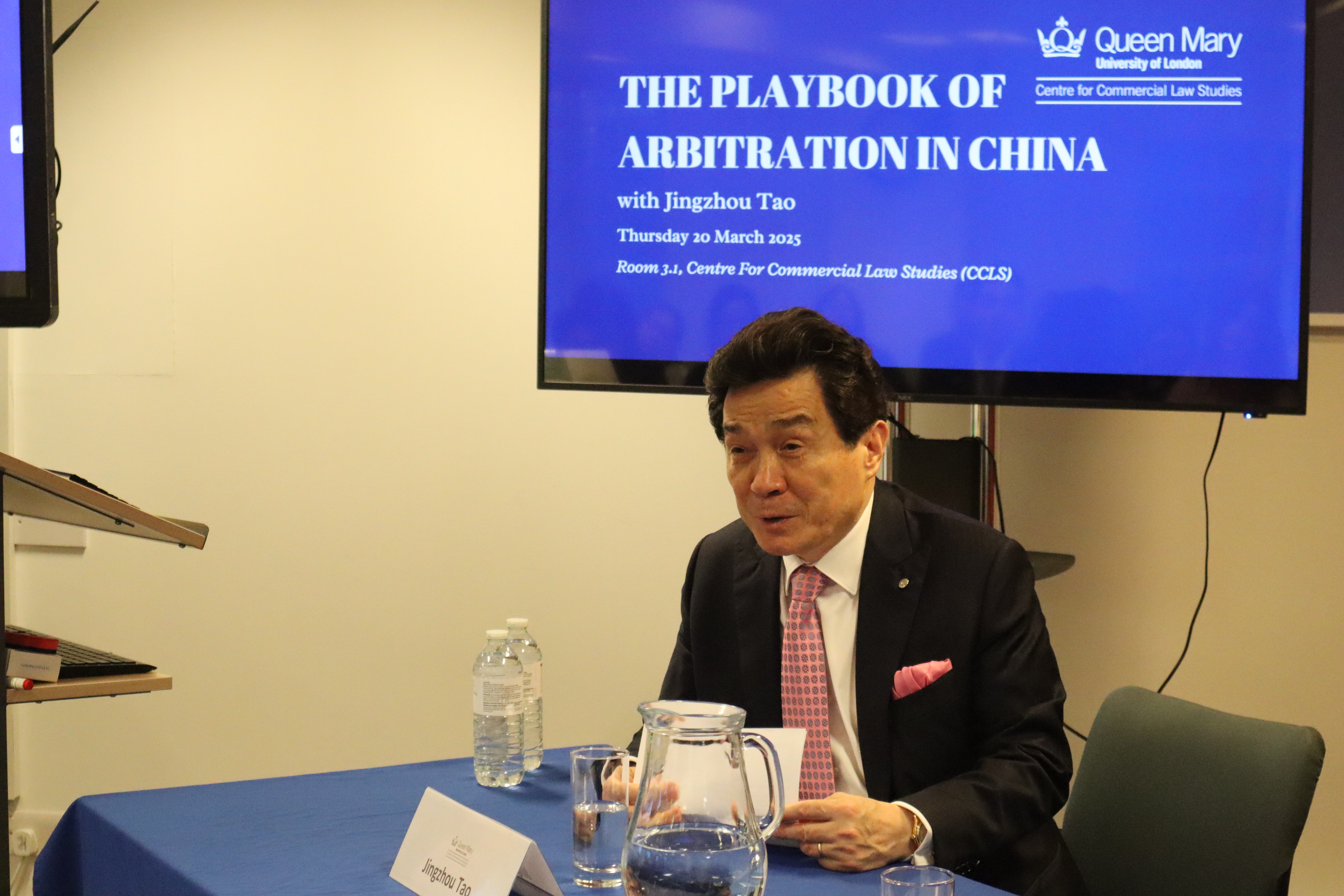 Jingzhou Tao talking at a panel table