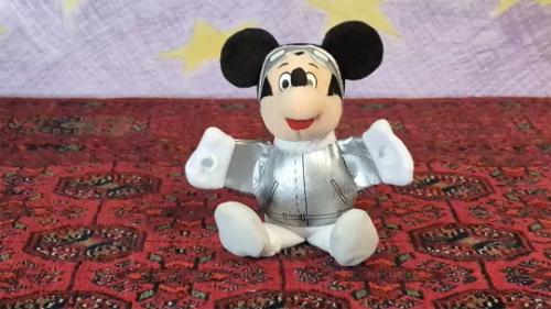 A plushie toy of Mickey Mouse on a carpet.