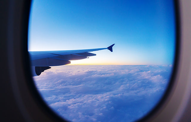 Looking out of an airplane window at a cloudy sunrise.