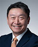 Paul NG smiling. He is wearing a suit and light orange tie.