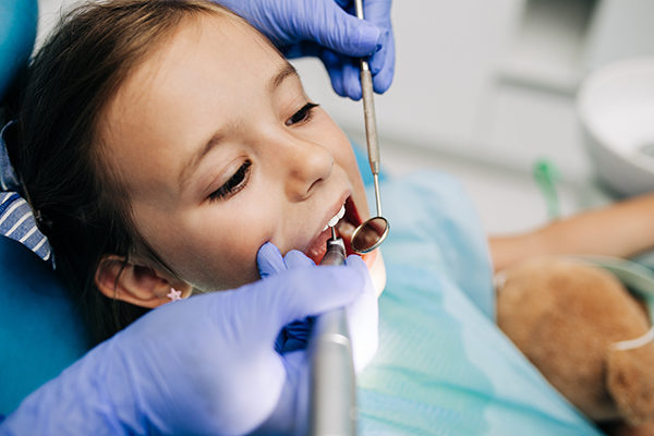 A young child having her mouth examined by a dentist