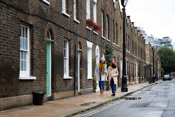 Photo of two women walking down a residential street in front of terraced housing