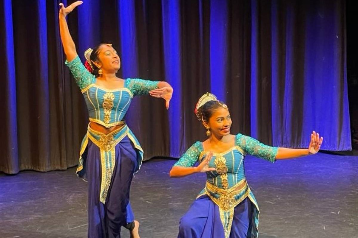 Two female dancers in blue costumes perform a Sri Lankan Kandyan dance