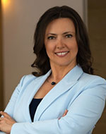 Żaneta Zemła-Pacud. She is smiling and has her arms folded, wearing a baby blue blazer.