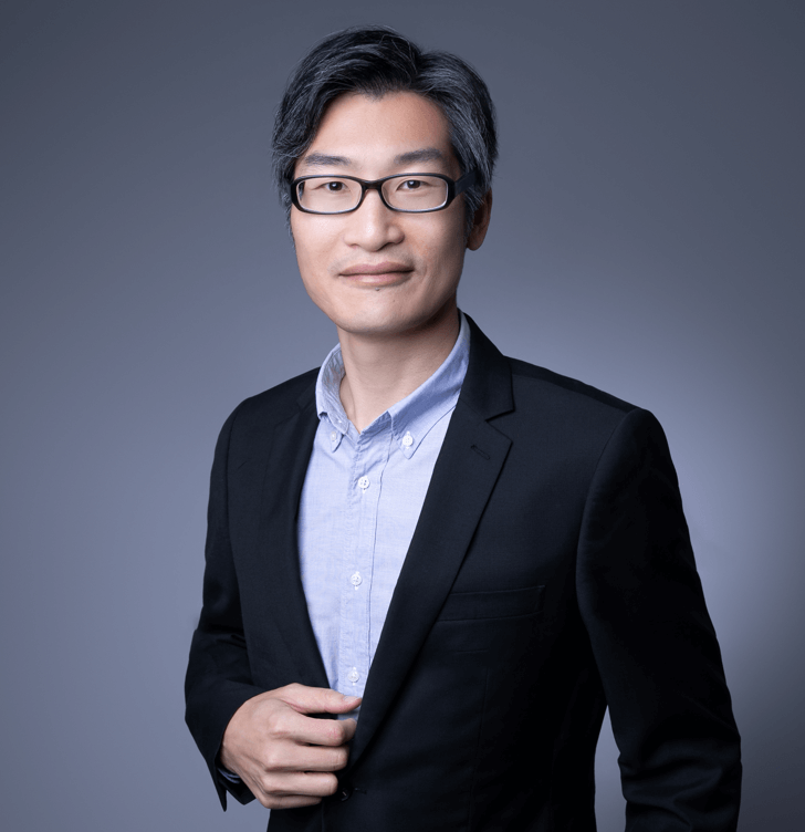 Alex Leung wearing a suit looking at camera