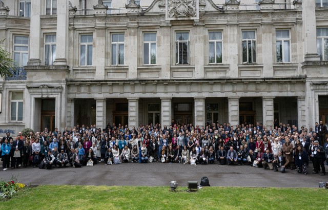 A big group of conference attendees standing in front of the Queen's building on Mile End campus