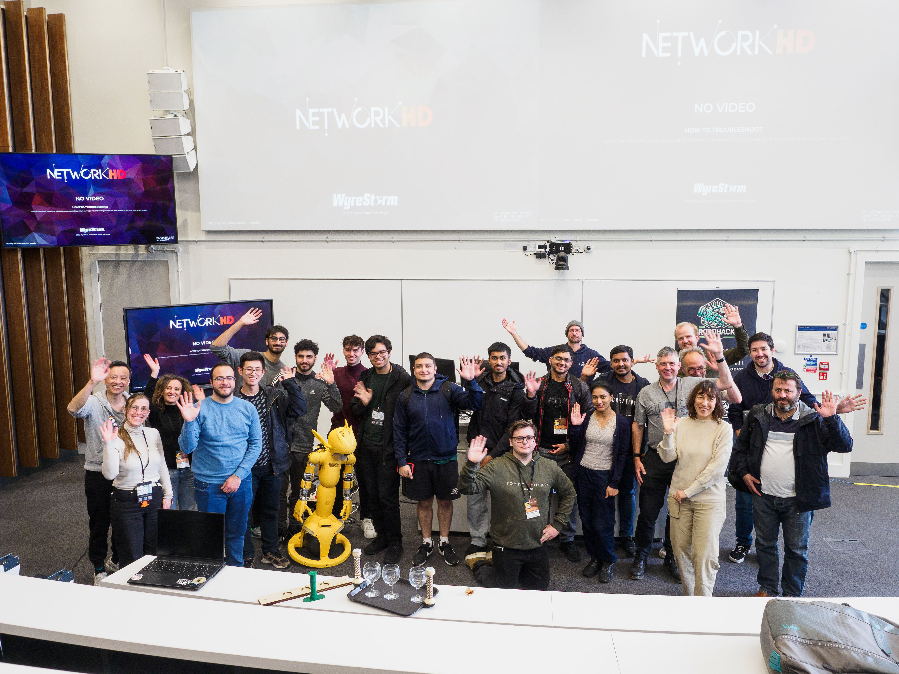 A big group of people at a Hackathon event with a robot