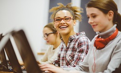 2 students smiling looking at computers