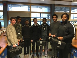 Group of students facing the camera holding cases