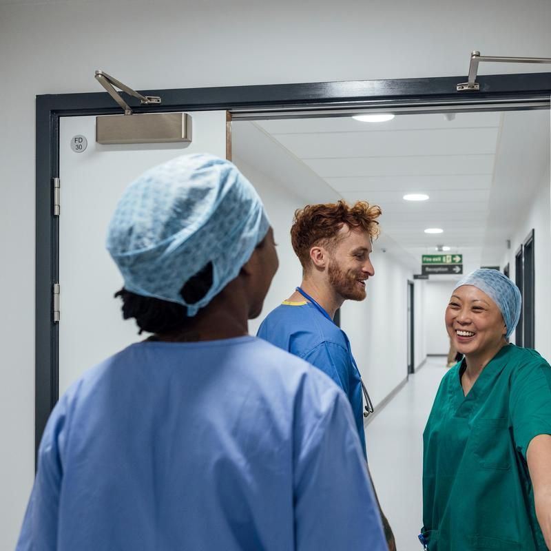 Three medical professionals chatting in a hospital corridor