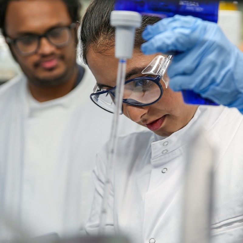 Two students in Blizard lab with one using lab equipment and the other watching