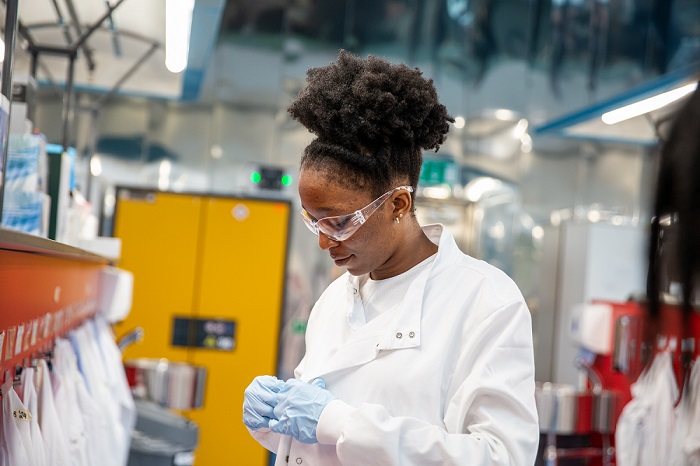 A photo of a women putting on her lab coat