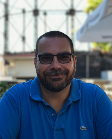 A picture of Prof Nikolas Lemos sitting outside at a cafe