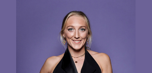 A picture of Saskia Budgett in smart dress against a purple background