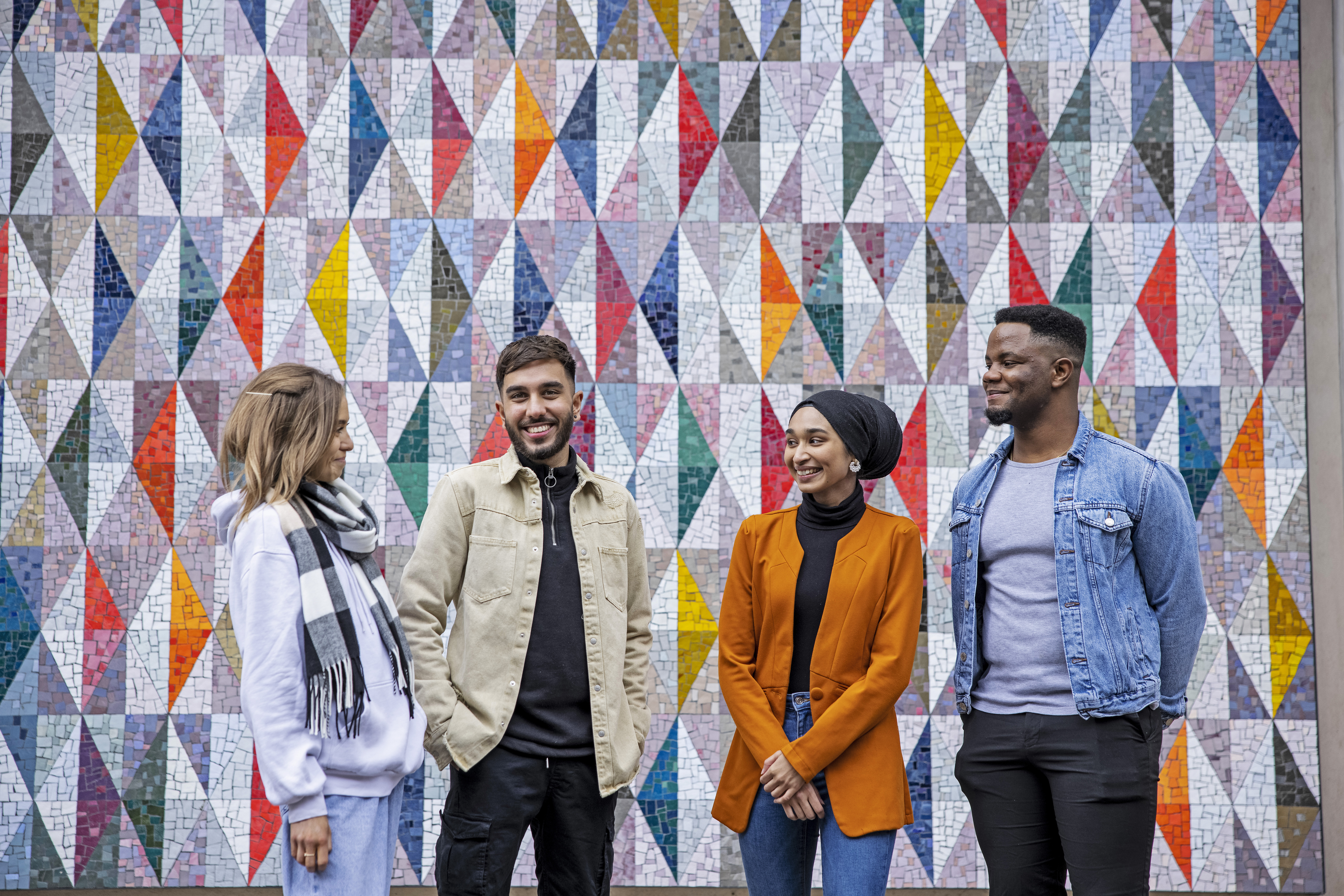 Four students standing together talking and smiling