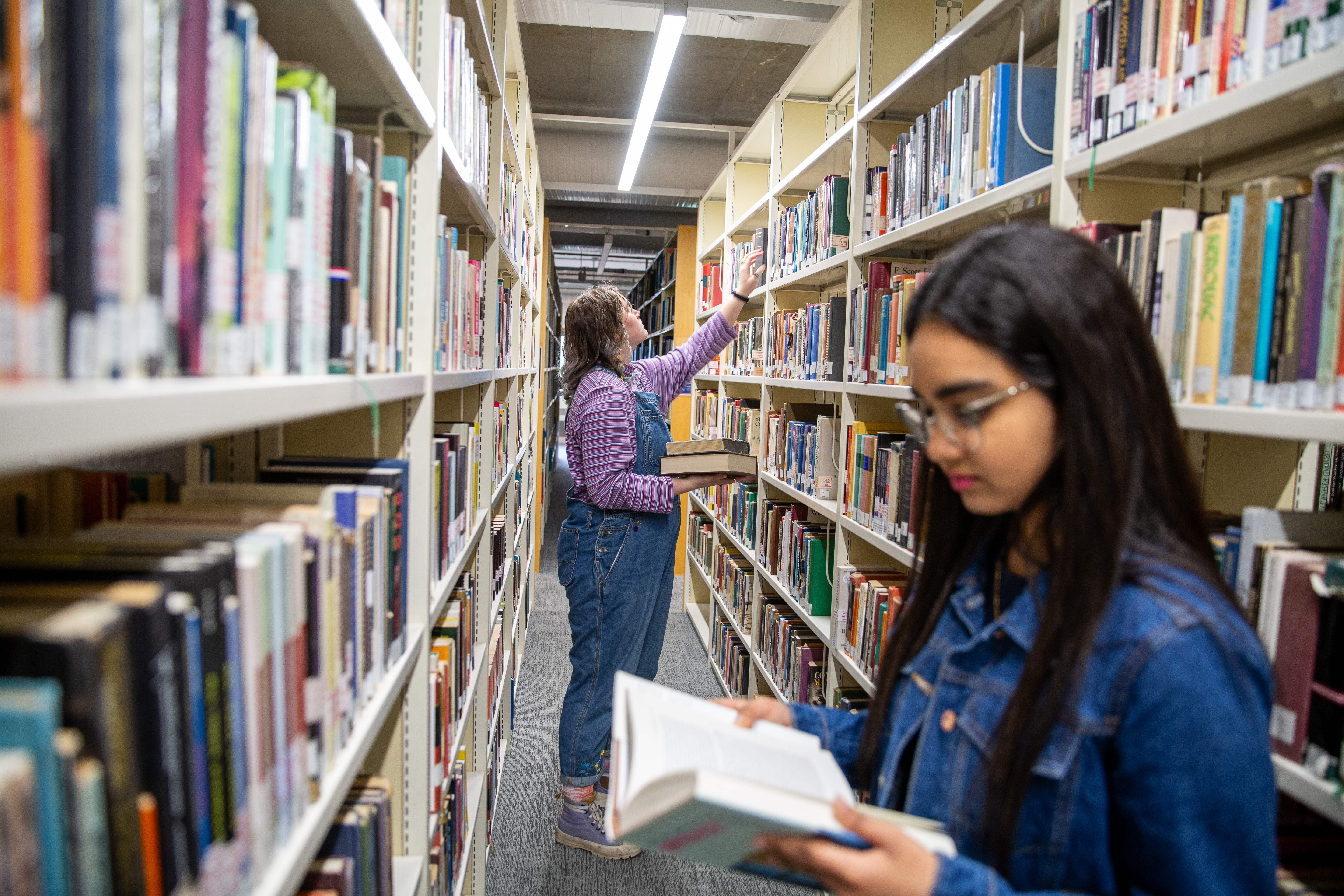 Two female students in a library looking at books