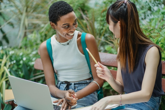 Two female students sat together laughing