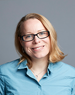 Frances Ridout. She is wearing glasses and a blue shirt. She is smiling.