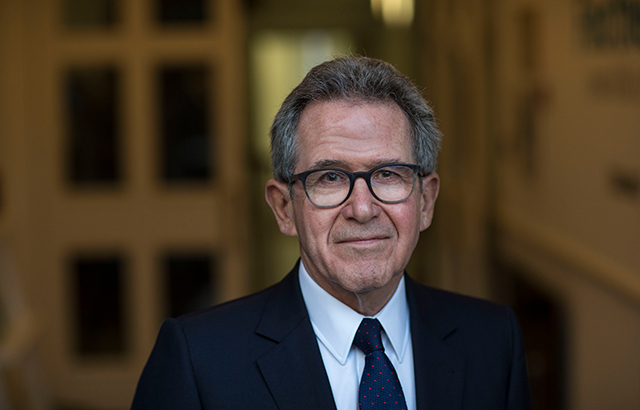 Lord Browne. He is facing the camera and wearing a suit, blue tie and glasses.