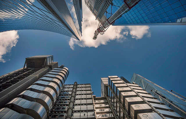 A photo looking directly up at glass office buildings from the street.