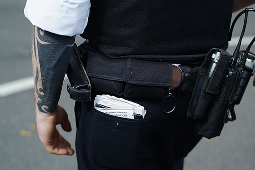 Behind view of a police officer's waist and gear at Nottinghill Carnival