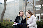 Queen Mary Law students reading a book outside on campus
