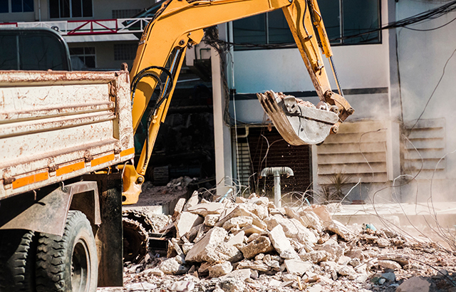 A bulldozer clearing away rubble in a residential area.