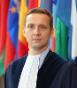 Judge Konrad Marciniak stood in front of country flags.