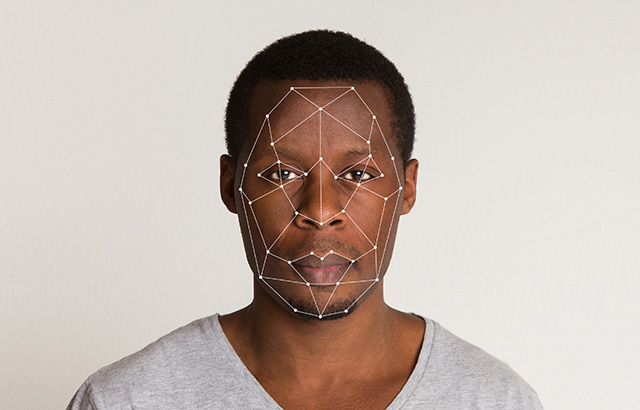 A black man facing the camera. He has dots across his face indicating his face is being scanned.