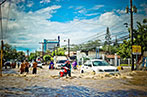 People walking and driving through a street flooded with water
