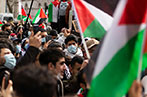 A protest for Palestine in London, with people wearing masks and holding Palestinian flags.