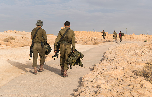 Israeli soldiers walking in the Masada desert.